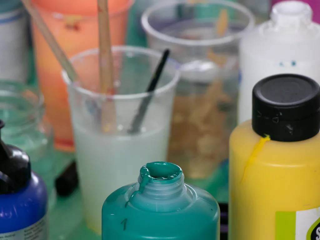 Farbflaschen und Becher auf einem Tisch.